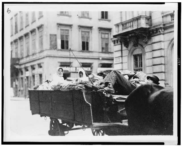 Man lying down on wagon seat, two women in back of wagon, Hungar