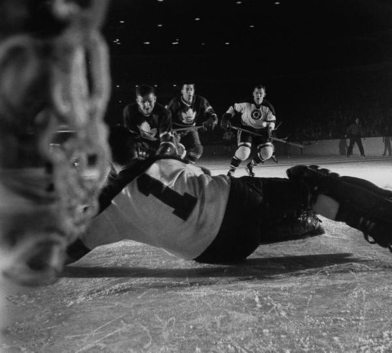 Ice Hockey player Al Rollins, intercepting puck with his body, d