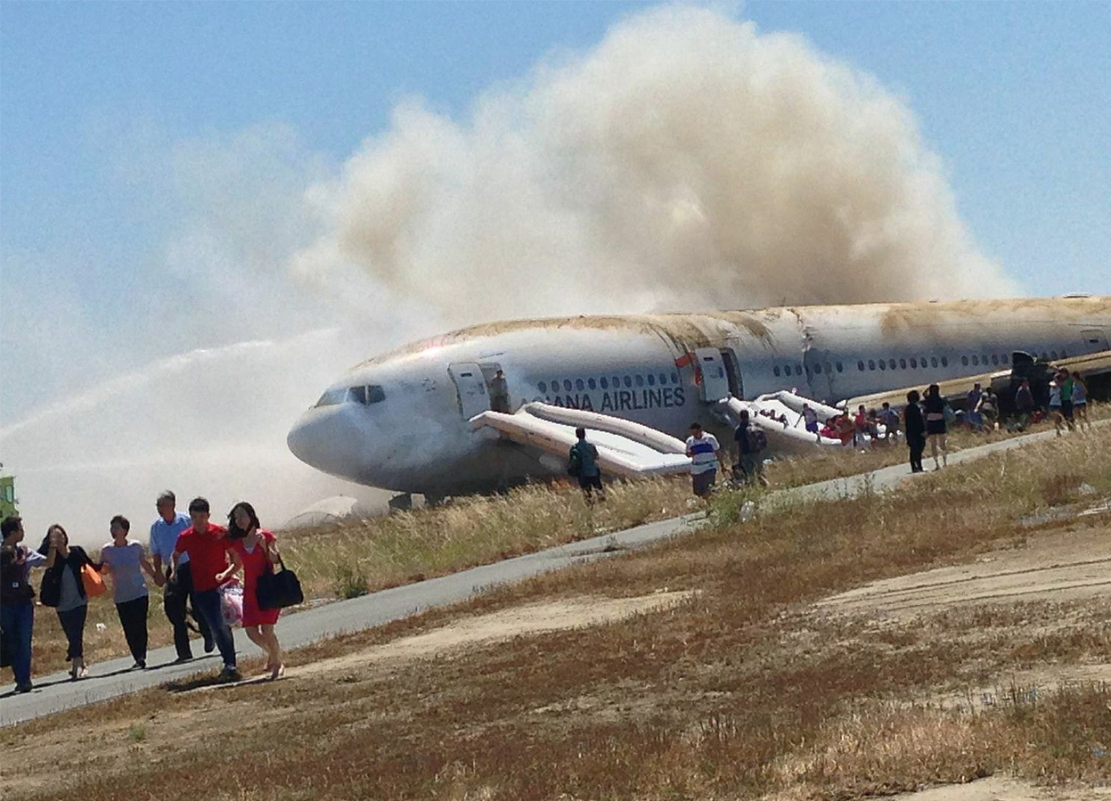 Passengers move away from the crash site of Astana flight 214, a