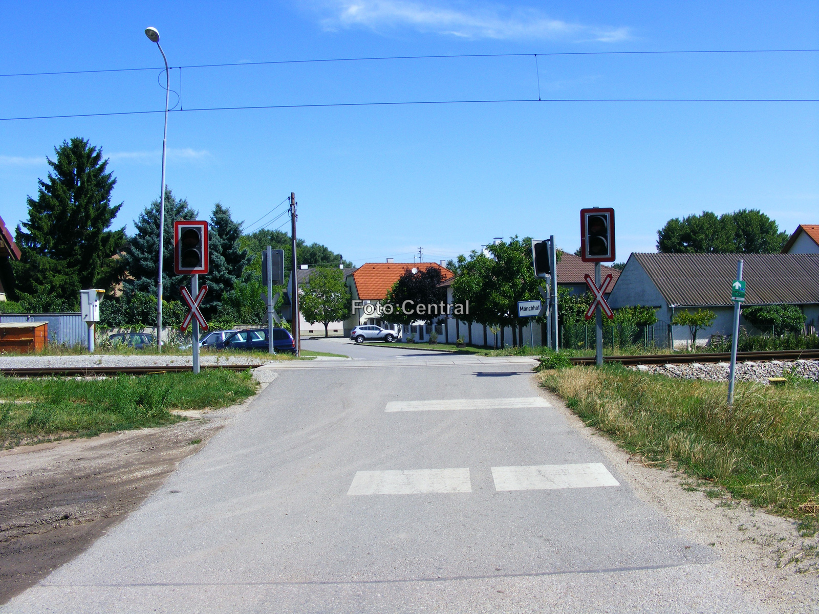 A megállóhelynél lévő vasúti átjáró Barátudvar centruma felé néz